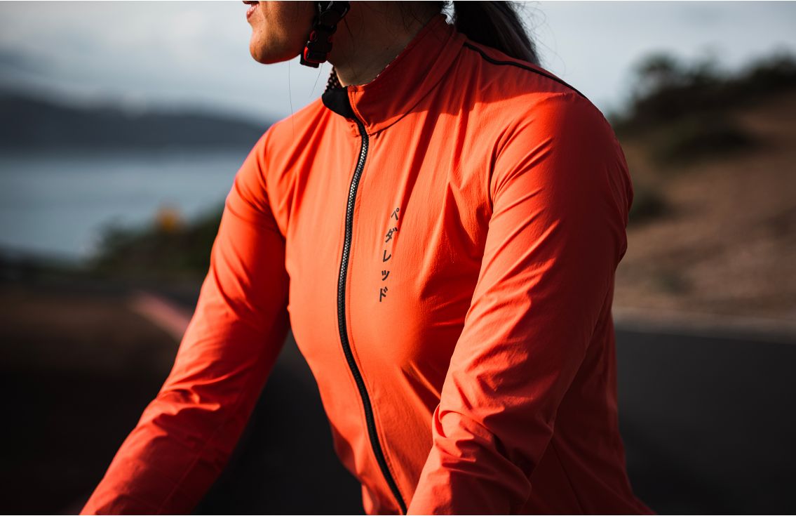 women water restistant cycling jacket brick red mirai pedaled in action